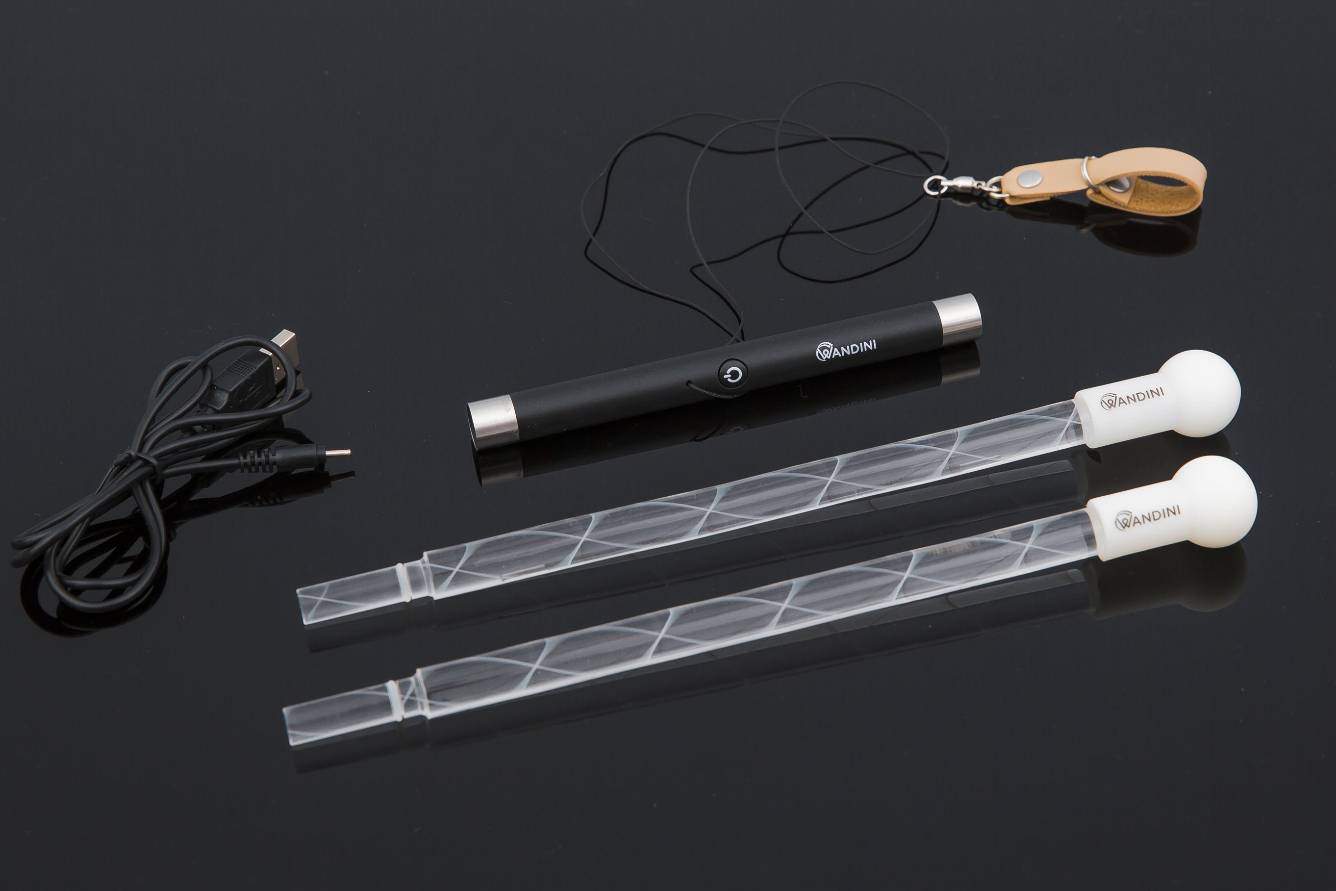 Components of the Wandini Glow.0 Magic LED Levitation Wand, including the wand itself, USB charging cable, and other accessories laid out on a dark background.