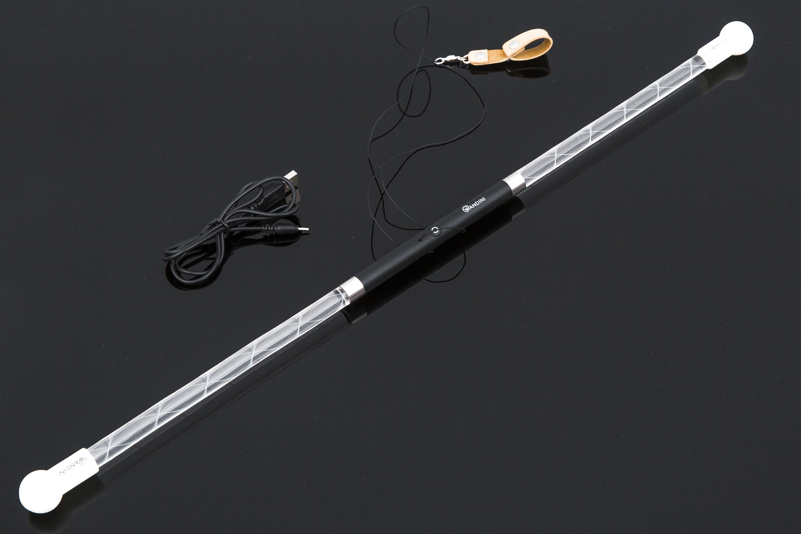 Close-up of the Wandini Glow.0 Magic LED Levitation Wand on a dark surface, showing the assembled wand along with a USB charging cable and wrist strap.